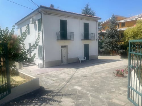 Appartamento bianco su due piani con persiane verdi e balconate, giardino pavimentato a Tales of Abruzzo ad Atessa, Italia