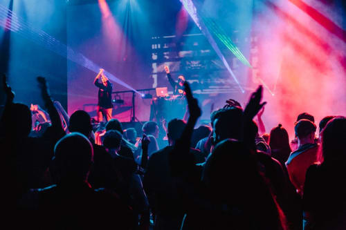 Concerto dal vivo vibrante con folla in silhouette che balla sotto luci di scena blu e rosa