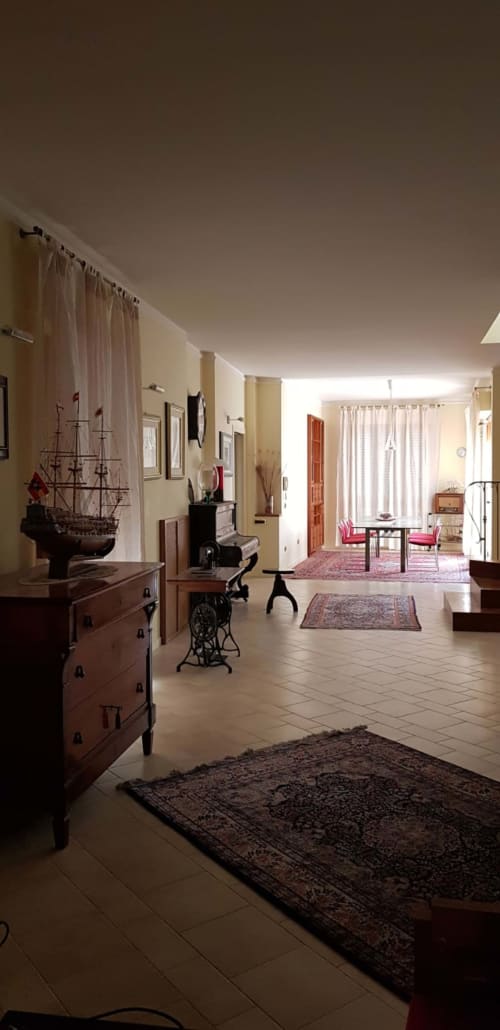 Lobby dell'hotel Tales of Abruzzo ad Atessa con mobili vintage, modellino di nave, tappeti rustici e eleganti tende color crema