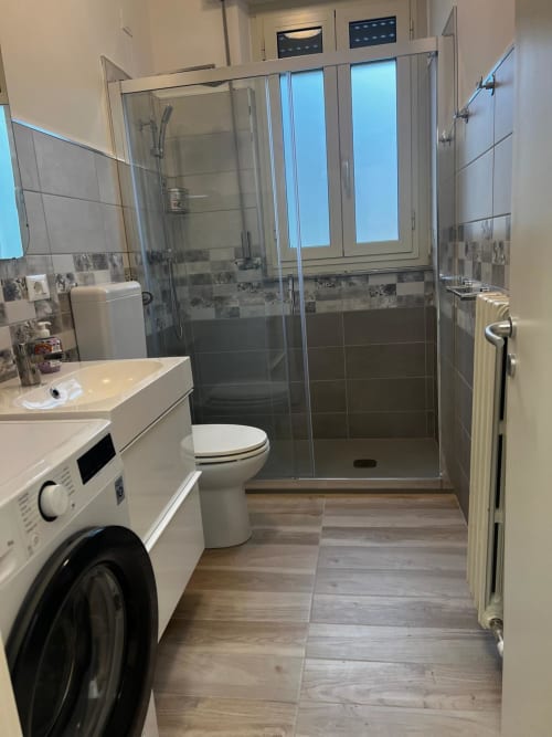 Bagno moderno con doccia walk-in, toilette, lavandino e lavatrice nell'appartamento Tales of Abruzzo ad Atessa, Italia