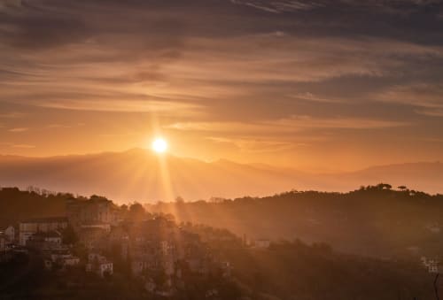 Tramonto su Campagnano di Roma con edifici storici sagomati contro il cielo dorato e colline ondulate