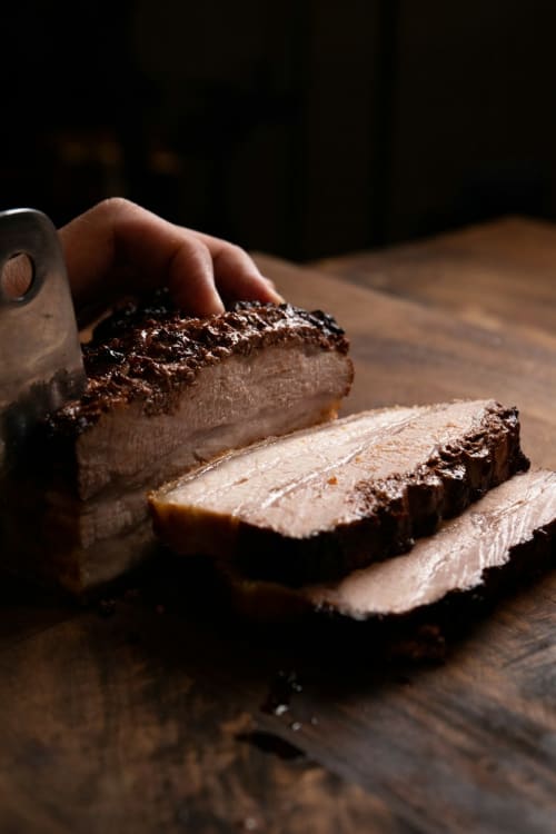 Mano che affetta l'anatra seared su tavola di legno, esperienza culinaria presso Co-Host Now Roma