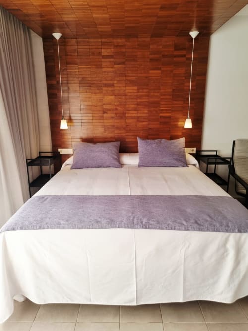 Modern bedroom at El Arrecife de Conil with double bed, purple pillows, wooden accent wall, and pendant lights in Conil de la