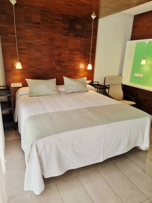 Modern bedroom at El Arrecife de Conil with double bed, wooden accent wall, pendant lights in Conil de la Frontera