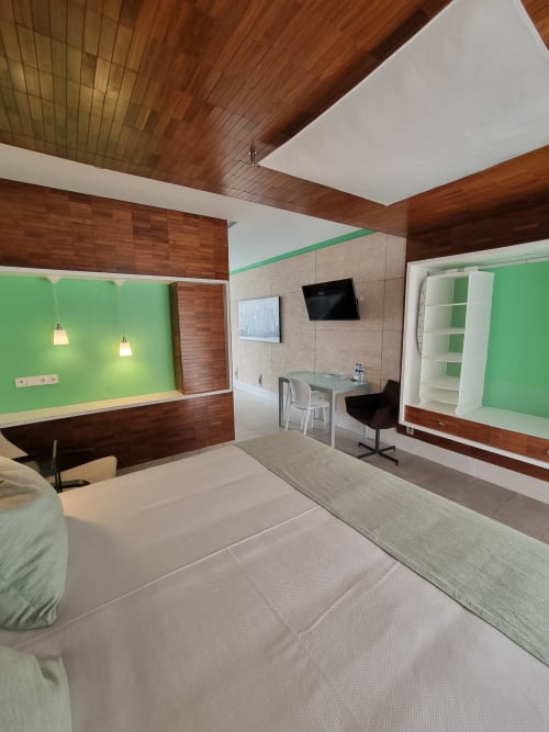 Modern hotel room Verde at El Arrecife de Conil with green accent wall, wooden ceiling, twin beds, work desk, and TV