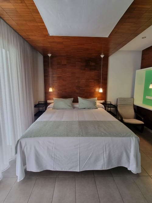 Modern bedroom at El Arrecife de Conil in Conil de la Frontera with wooden accent wall, double bed, and pendant lighting