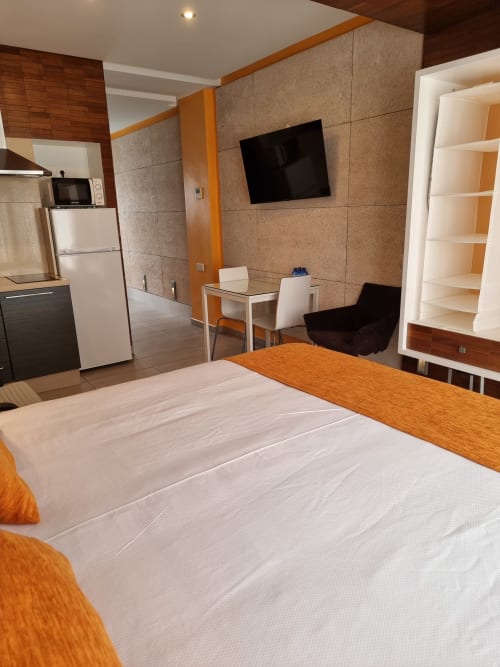 Modern apartment bedroom in Naranja room at El Arrecife de Conil, Conil de la Frontera with double bed, kitchenette, TV, and
