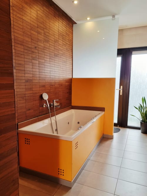 Modern bathroom at El Arrecife de Conil with orange bathtub, red tiled walls, and rainfall shower in Conil de la Frontera,