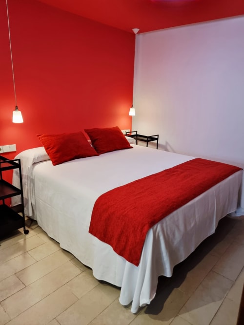 Modern red bedroom at El Arrecife de Conil hotel in Conil de la Frontera with white bedding and pendant lights