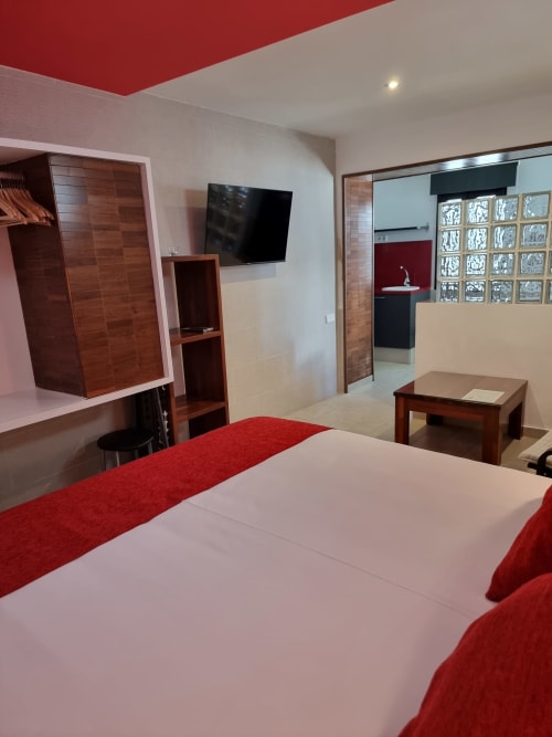 Modern red and white apartment bedroom at El Arrecife de Conil with TV, wooden furniture, and city views in Conil de la