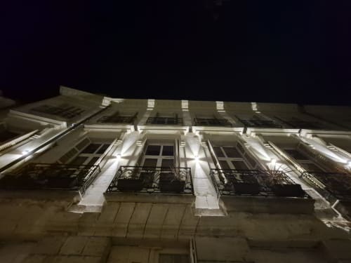 Façade illuminée de l'Hôtel Du Cygne la nuit à Tours, avec fenêtres classiques et balcons en fer forgé