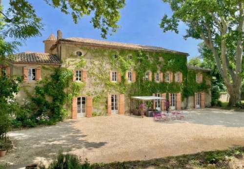 Château De Sienne, une chambre d'hôtes en pierre et brique de terre cuite à Chusclan, France, avec façade couverte de lierre et cour intérieure.