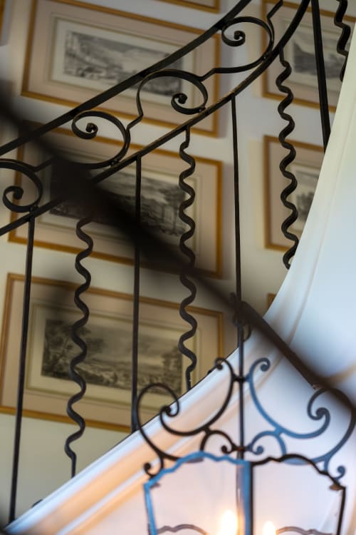 Elegante barandilla de escalera en hierro forjado negro con ornamentación de volutas en Le Domaine du Fortin en Ménerbes, Francia