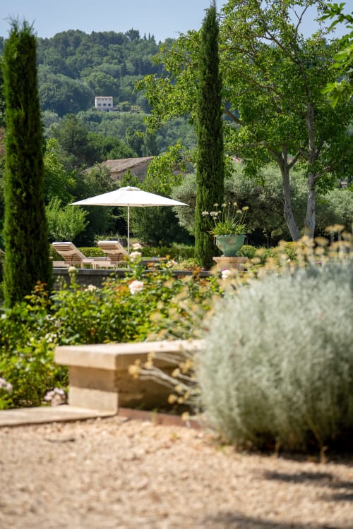 Jardín toscano en Le Domaine du Fortin con tumbonas, sombrilla, cipreses y vistas al campo de Ménerbes