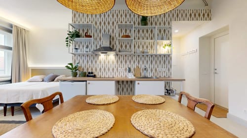 Modern apartment dining area at tARTu Stays with wooden table, woven placemats, and kitchenette with white cabinetry in