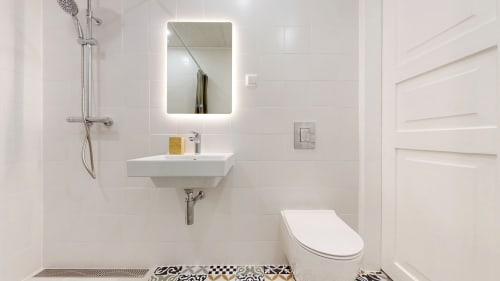 Modern bathroom in tARTu Stays apartment featuring white sink, toilet, shower, and illuminated mirror in Tartu city center
