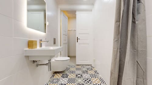 Modern bathroom in tARTu Stays apartment with white tiles, patterned floor, sink, toilet, and shower in Tartu