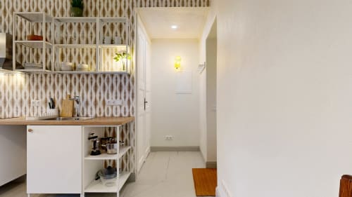 Modern kitchen area with white cabinetry, geometric backsplash, wooden countertop, and open shelving at tARTu Stays apartment