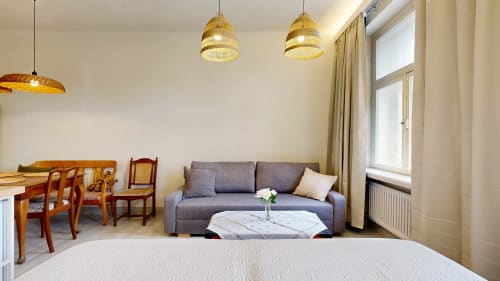 Modern Tartu apartment with gray sofa, wooden dining table, and gold pendant lights, city view