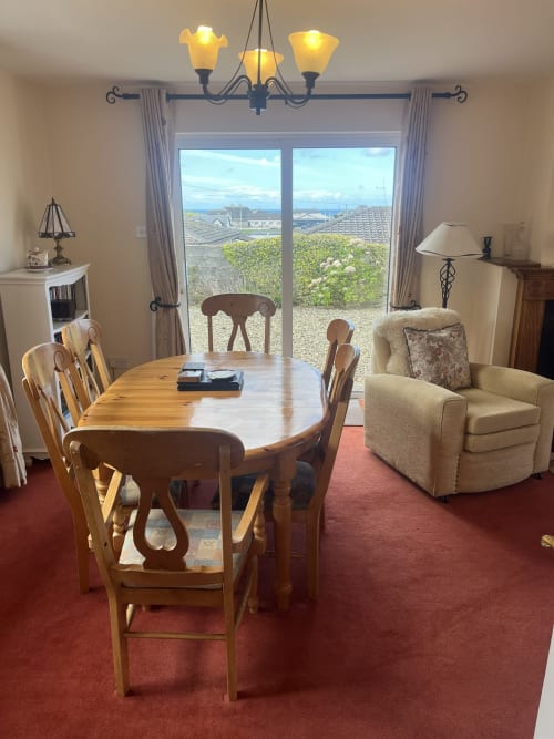 Bright dining area at Ard Na Mara, Co. Clare, with wooden table, sea views through glass doors, and coastal landscape
