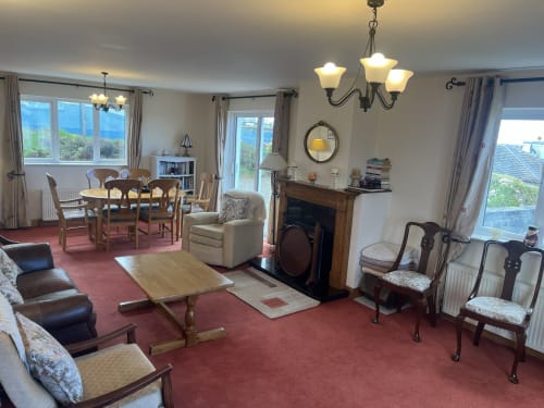 Spacious living area at Ard Na Mara, Bucket & Spade, Co. Clare with fireplace, dining table, and sea views