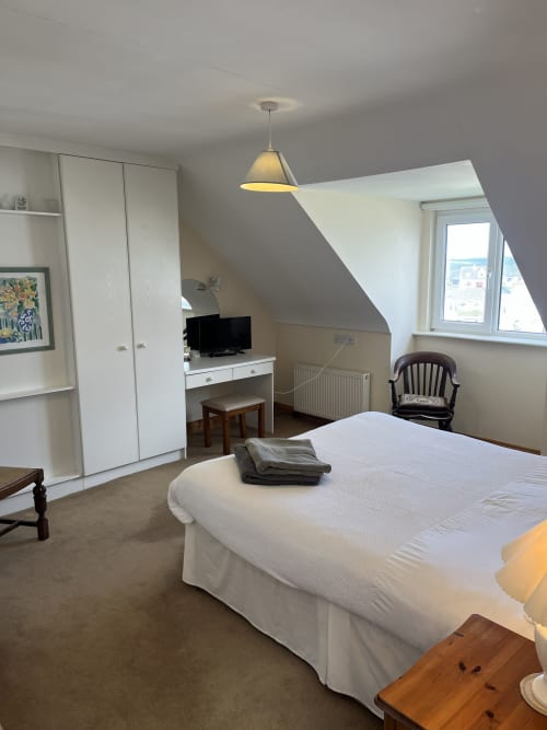 Bright Ard Na Mara bedroom with white bed, TV desk, wardrobe, sea view window, and pendant lighting in Co. Clare