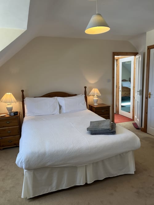 Bright bedroom at Bucket & Spade with white bedding, wooden furniture, pendant light, and sea view access in Co. Clare
