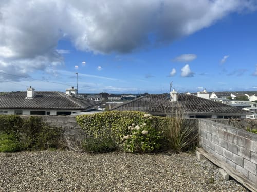 Ard Na Mara apartment terrace with sea view in Co. Clare, Ireland, featuring gravel patio and residential roofline