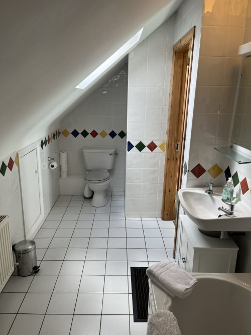 Spacious bathroom in Ard Na Mara apartment at Bucket & Spade hotel, Co. Clare with white tiles and colorful diamond accents