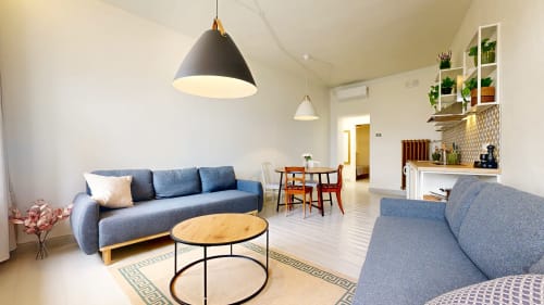 Modern Tartu apartment living room with blue sofa, dining area, kitchen, and stylish pendant lighting