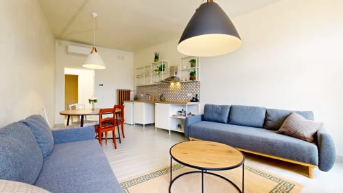 Modern apartment living room at tARTu Stays Tartu with blue sofa, kitchen, dining area, and pendant lighting