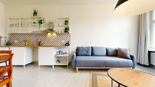 Modern apartment living area at tARTu Stays with gray sofa, kitchen, dining table, and white shelving in Tartu
