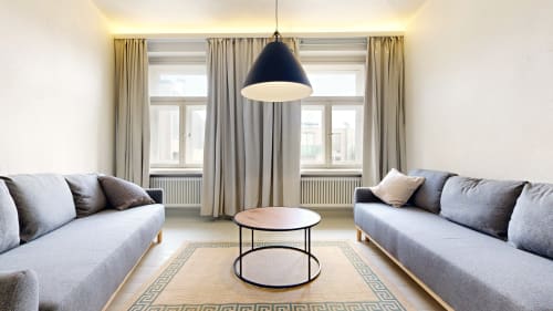 Modern apartment sitting area at tARTu Stays with gray sofas, black pendant light, and city view windows in Tartu