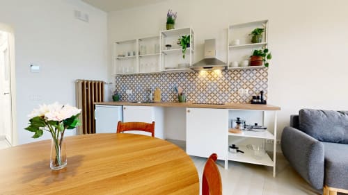 Modern kitchen and dining area in tARTu Stays apartment with wooden table, white cabinetry, patterned backsplash, and living