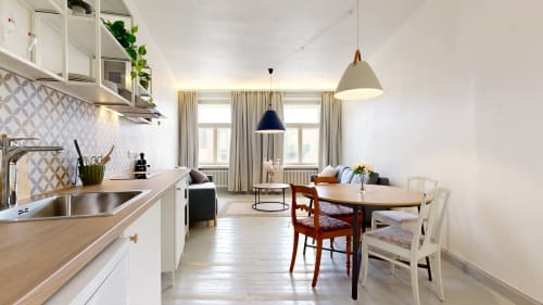Modern open-plan kitchen and dining area at tARTu Stays apartment in Tartu with white cabinetry, wooden dining table, and