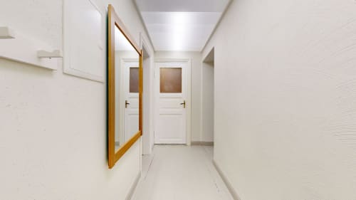 Modern hallway in tARTu Stays apartment with white walls, wooden-framed mirror, and white doors with glass panels in Tartu