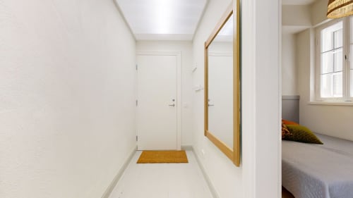 Bright hallway entrance in tARTu Stays apartment with white walls, wooden mirror frame, and brown welcome mat leading to
