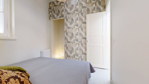 Modern bedroom at tARTu Stays City Center with patterned accent wall, gray bed, white closet door, and contemporary décor in