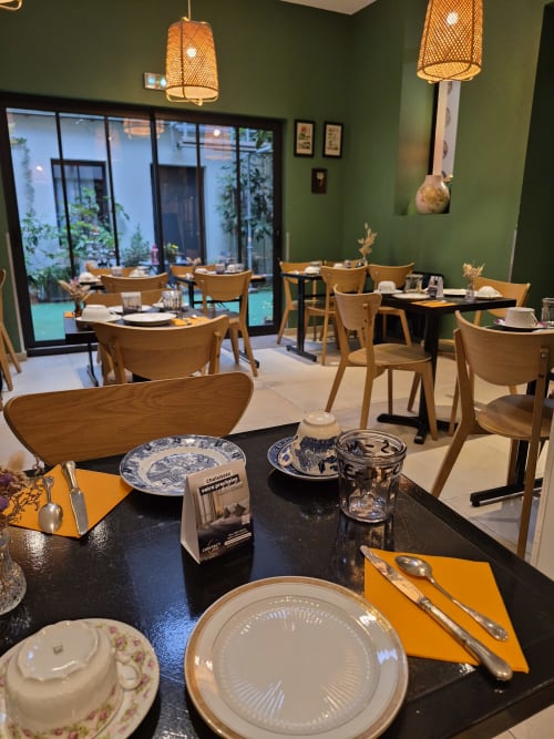 Elegant dining room at Hôtel Du Cygne in Tours with green walls, wooden chairs, and black tables set with fine dining