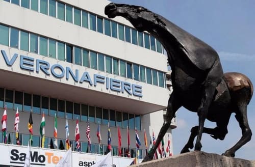 Black horse sculpture outside Veronafiere building with international flags in Verona
