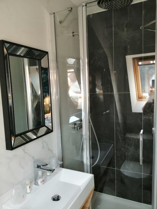 Salle de bains moderne à l'Hôtel Du Cygne Tours avec lavabo en marbre, miroir à cadre noir et douche vitrée