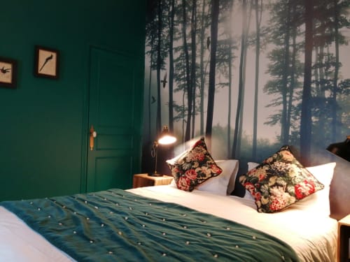 Chambre élégante à l'Hôtel Du Cygne Tours avec fresque forestière, porte verte, coussins décor et éclairage ambiant