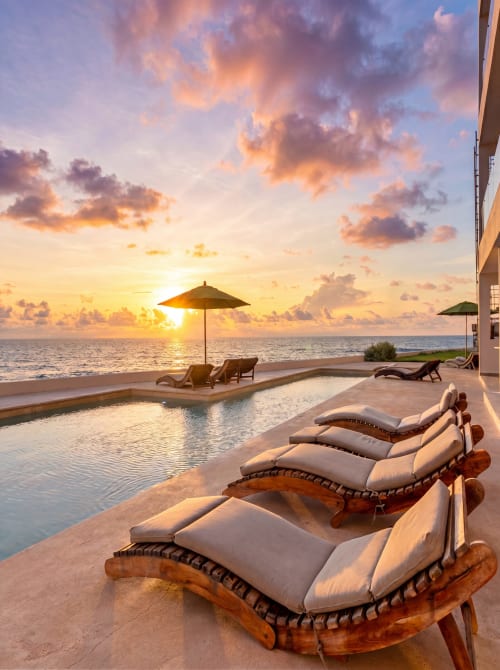 Sunset view at Malkita Sol oceanview apartment with lounge chairs, infinity pool, and beach access in Highland Mills