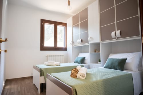 Modern twin bedroom in LikeHome Gelsomini villa near Ferrara with built-in storage and sea view window