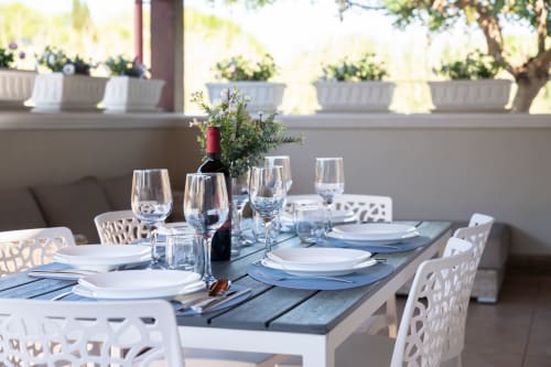 Elegant outdoor dining table at sea-view villa near Ferrara, Italy, set with wine glasses, white plates, and fresh flowers