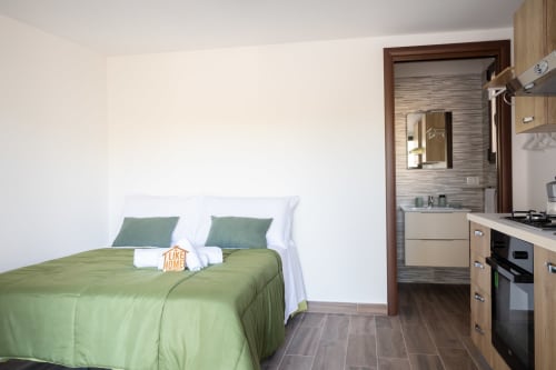 Modern villa bedroom with green bedding, en-suite bathroom, kitchenette, 400m from sea in Ferrara