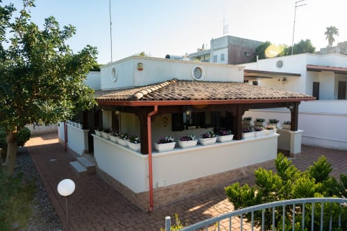 Coastal villa terrace in Ferrara with covered dining area, potted flowers, and sea view near beach