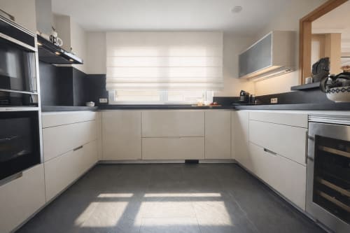 Cocina moderna con armarios blancos, encimeras negras y electrodomésticos de acero inoxidable  Toxiña de Holibai, Baiona