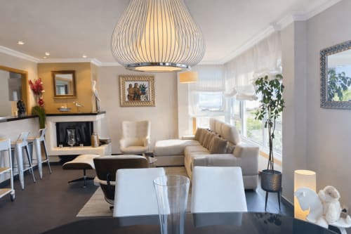 Moderno salón de la casita Toxiña en HoliBai, Baiona con vistas al mar, chimenea, mobiliario beige y lámpara de diseño