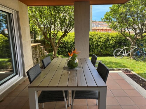 Comedor en terraza cubierta, zona verde y bicicletas. Holibai Toxiña Alquiler en Baiona